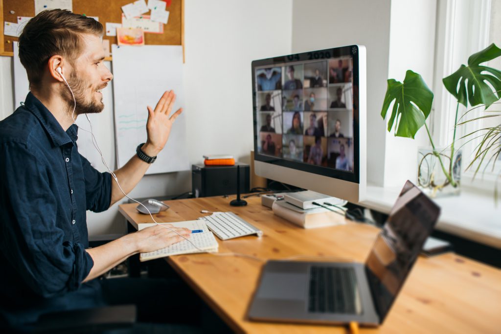 Business video conferencing. Young man having video call via computer in the home office. Multiethnic business team. Virtual house party. Online team meeting video conference calling from home